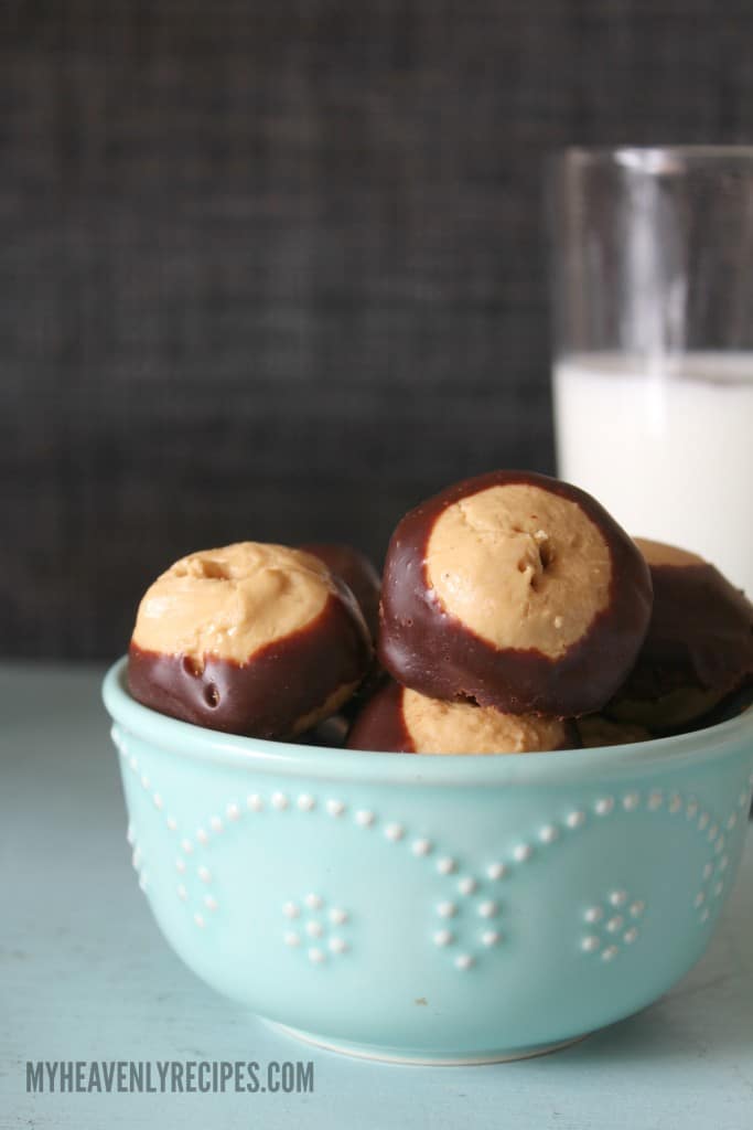 homemade buckeyes in a light blue bowl with a glass of milk in the background