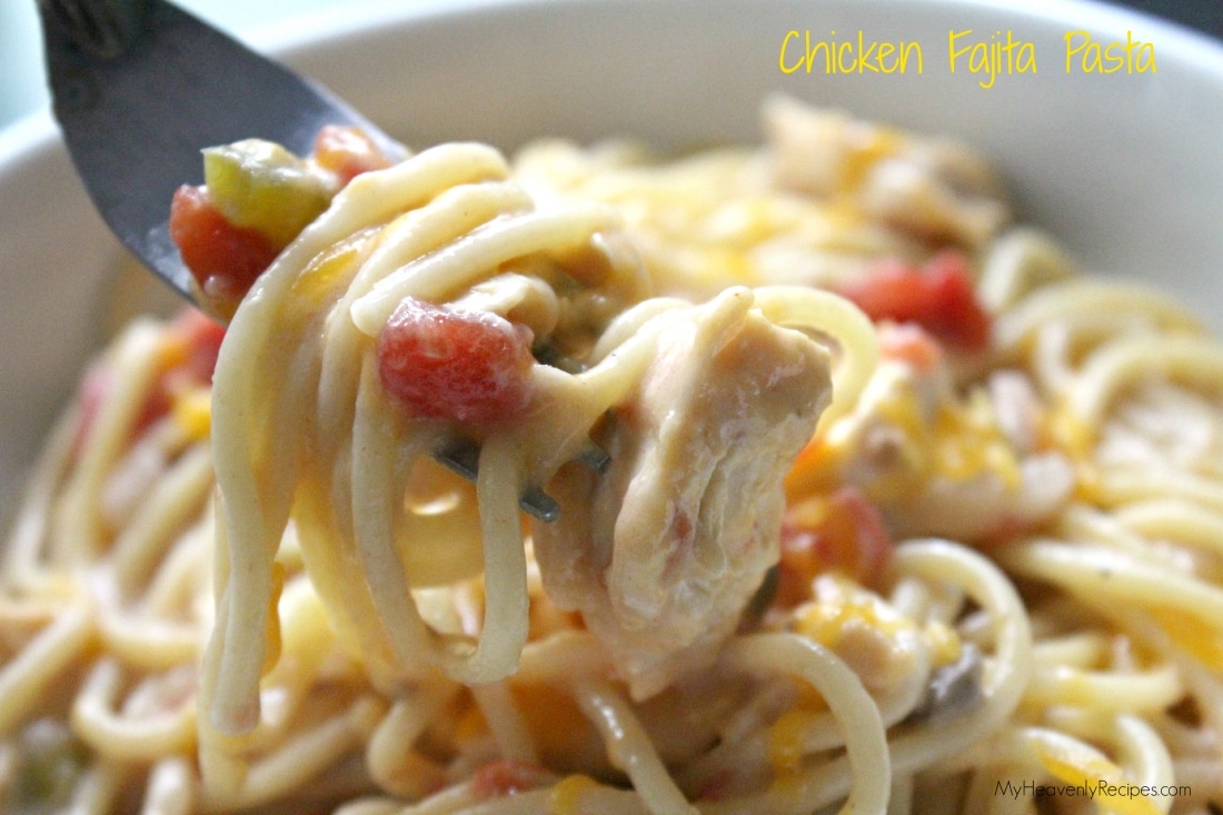 fork holding up crock pot chicken fajitas pasta over top white bowl containing crock pot chicken fajitas pasta