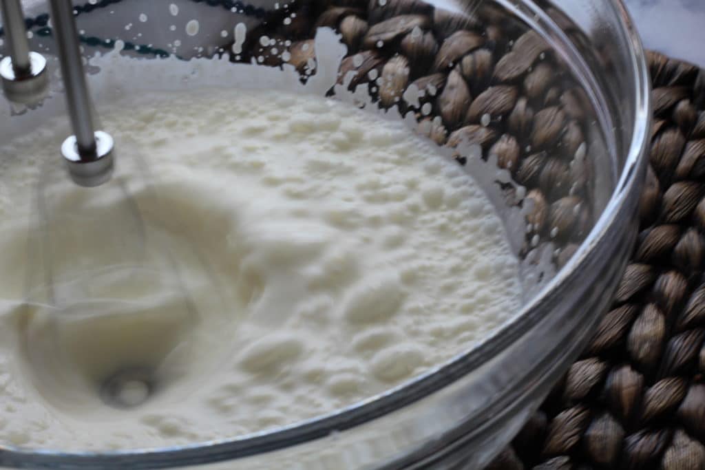 handheld mixer whisking heavy cream in a bowl
