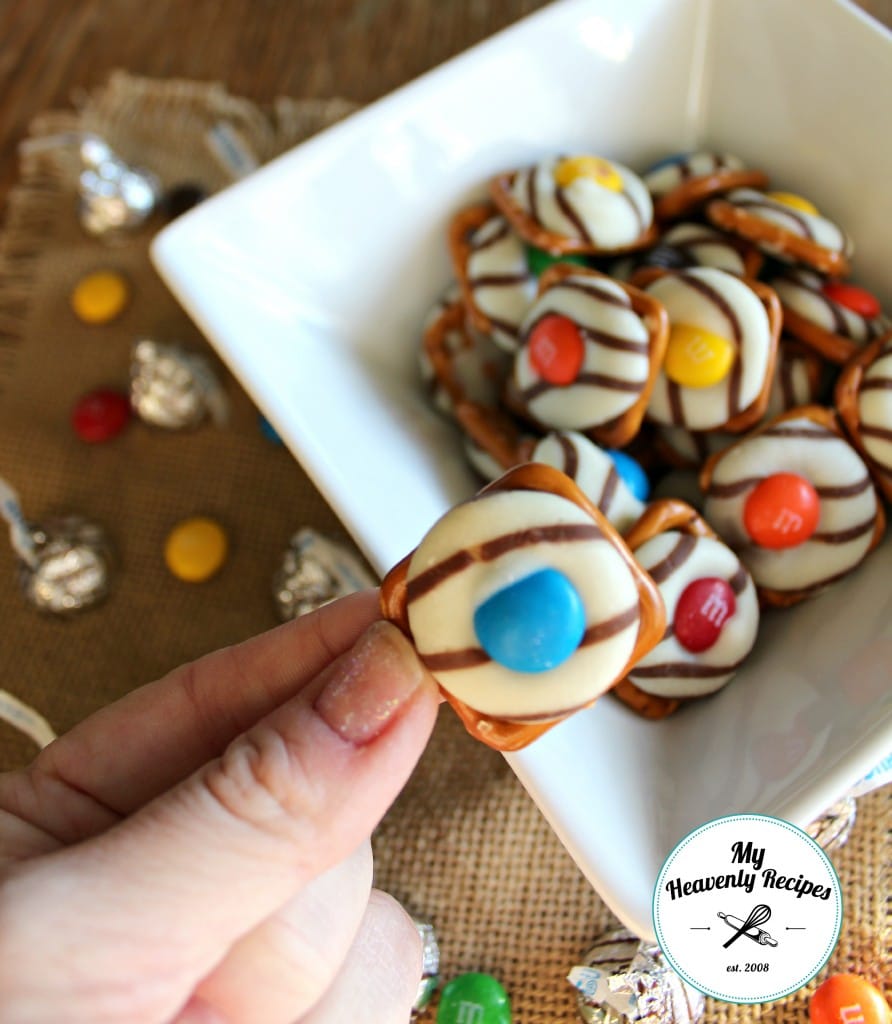 bowl of square pretzels with hershey kisses melted and a M&m