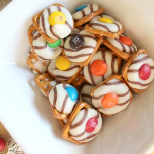 hershey kiss pretzels in a bowl white and m&m's on top of striped hershey kisses and pretzel