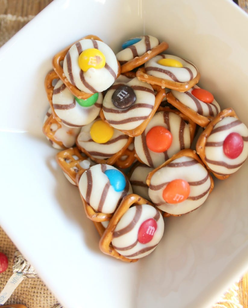 hershey kiss pretzels in a bowl white and m&m's on top of striped hershey kisses and pretzel