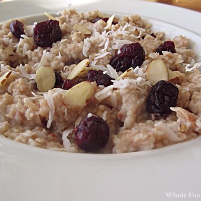 a bowl of steel cut oatmeal topped with coconut, almonds and dried fruit