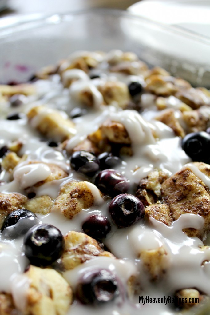 cinnamon roll french toast bake recipe with blueberries in clear baking dish and icing drizzled on top