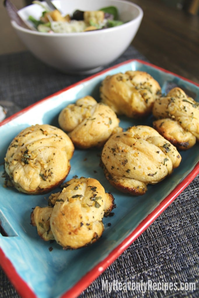 garlic knots on a platter with salad in background