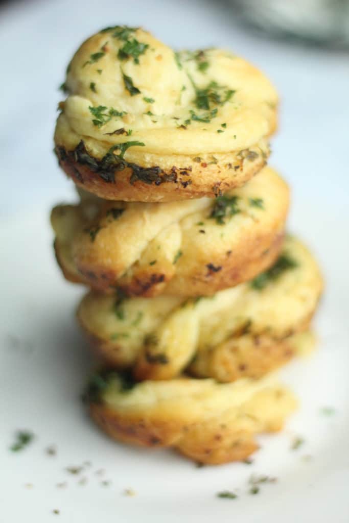 garlic knots stacked on top of each other on white plate