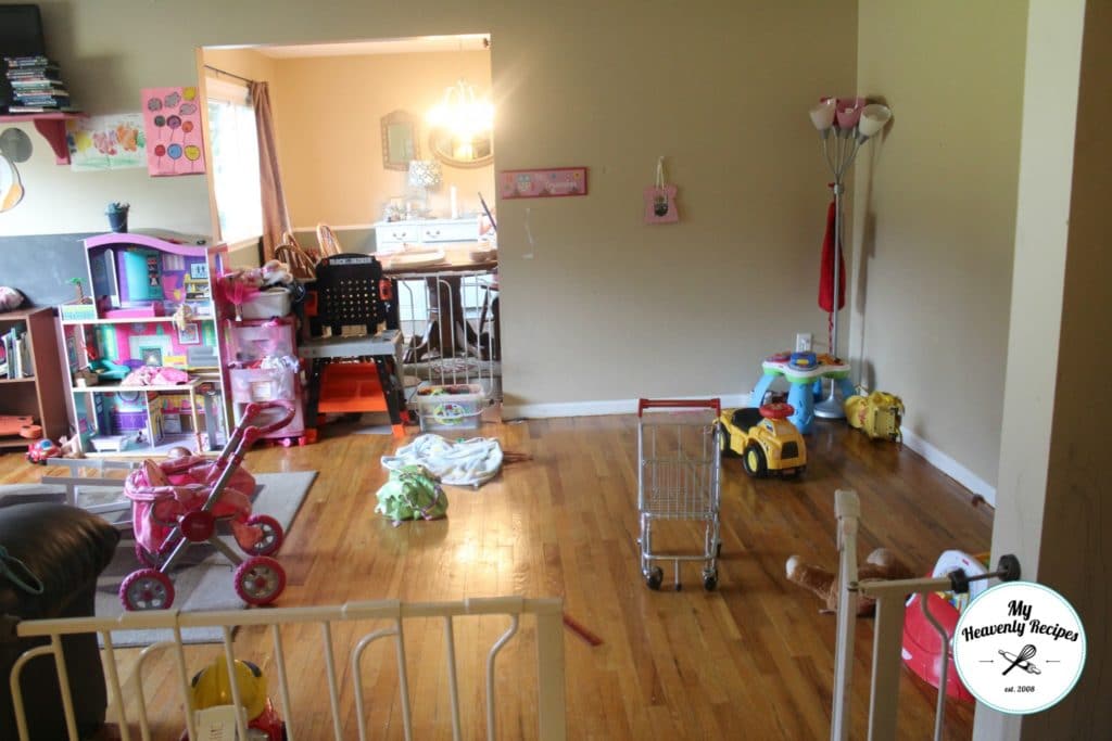 a messy playroom with a barbie house, baby strollers and toys