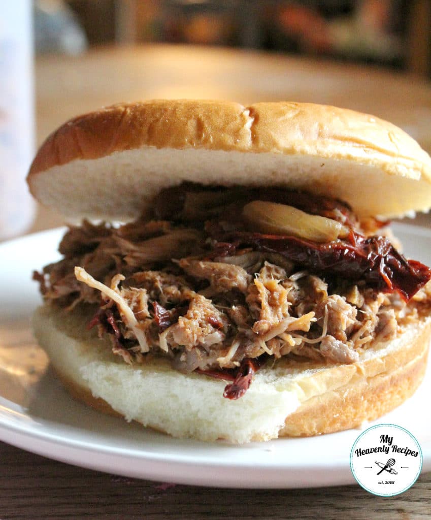 spicy pulled pork sandwich on a bun served on a white plate