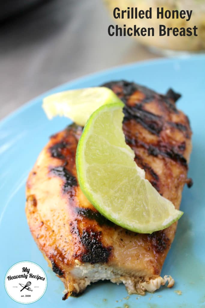 grilled chicken breast with a lemon peel on top served on a blue plate