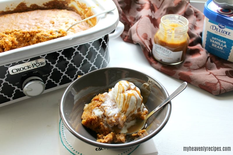 pumpkin spice dump cake in gray bowl with caramel sauce and crock pot on left side showing how the spice cake was cooked along with ice cream on the side