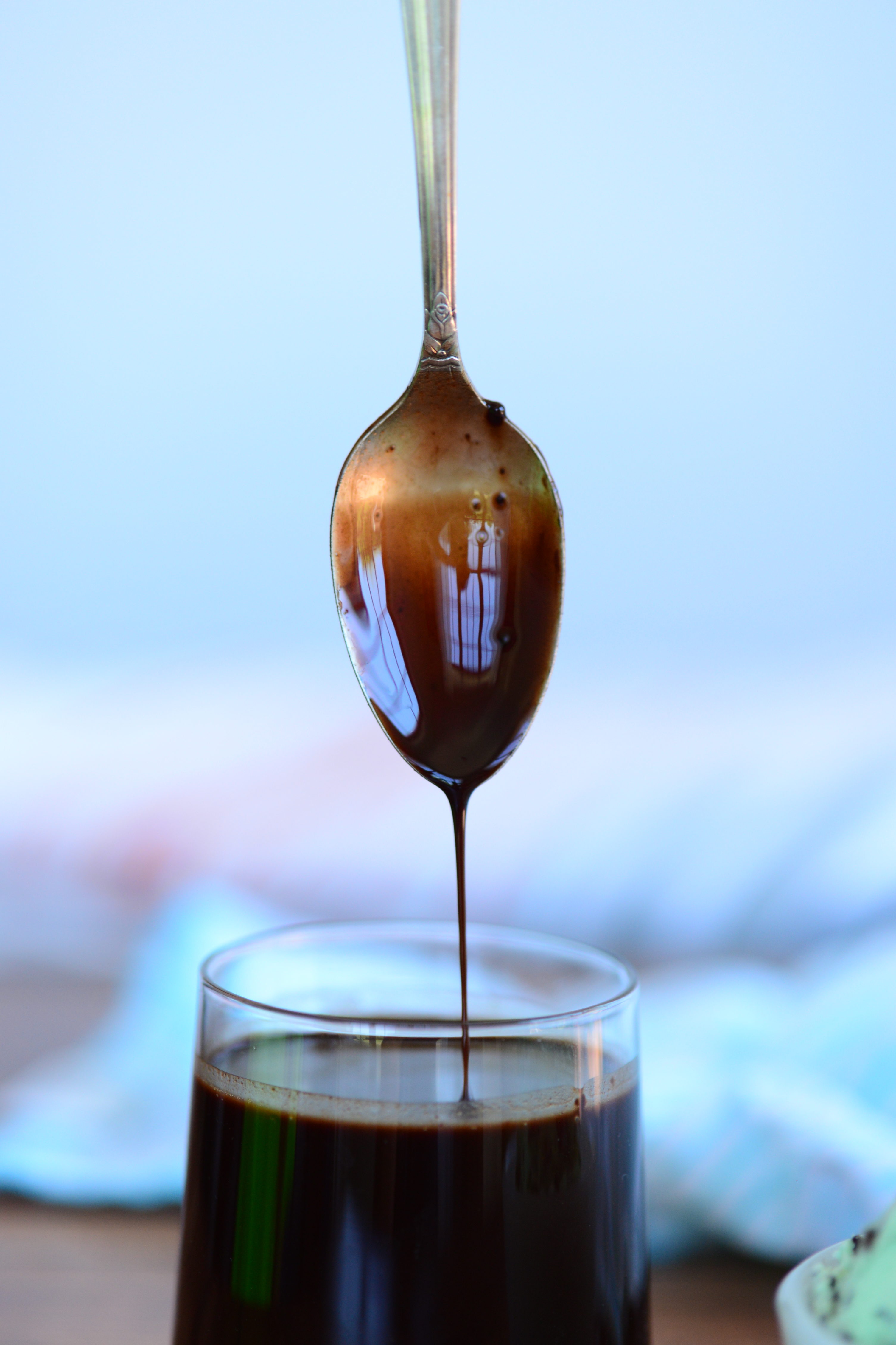 spoon dipped in glass with homemade chocolate syrup