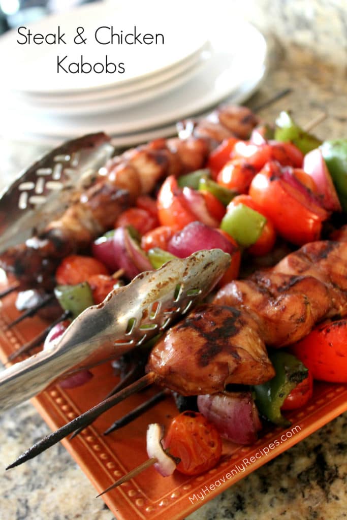 steak and chicken kabobs cooked on the grill, plated on a orange plate and tongs with white plates in background for servving