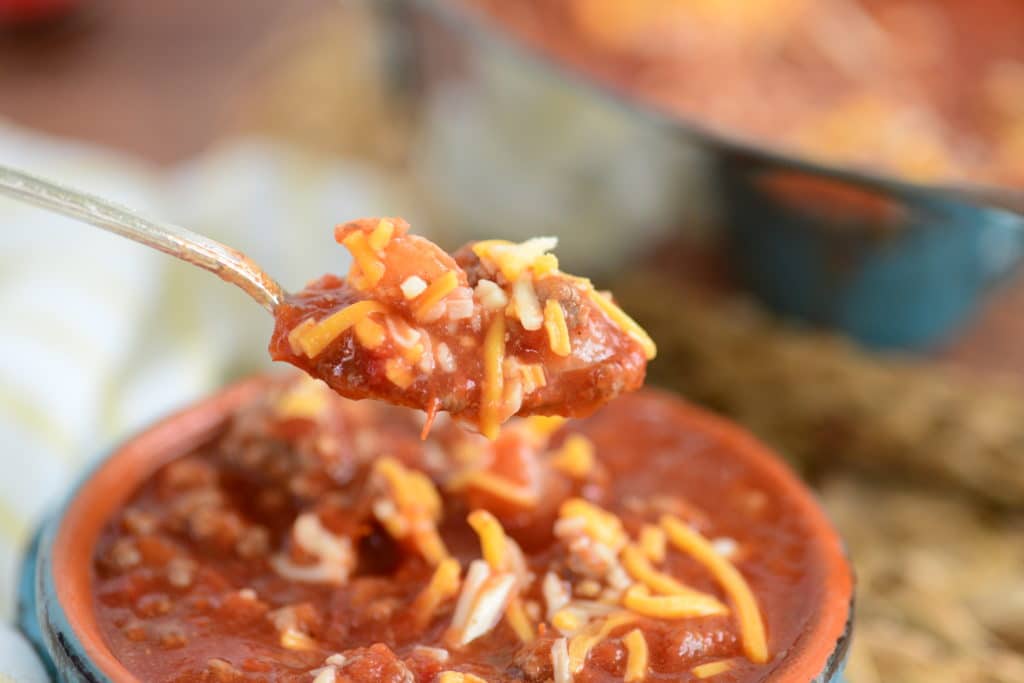 chili recipe on spoon with blue bowl of chili in background