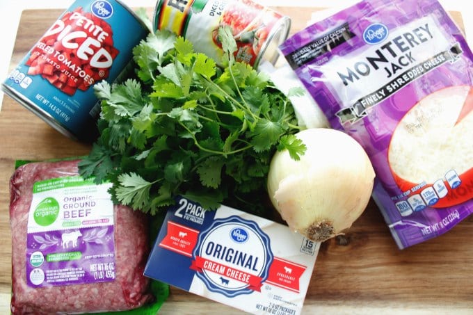 ingredients for taco soup on a cutting board including ground beef, cream cheese, and tomatoes