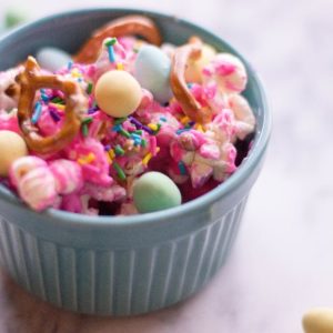 closeup of blue pastel bowl containing waster popcorn with pretzels and pastel candies on top