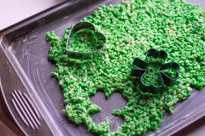 st. patrick's day dessert on top of a baking sheet being cut out with cookie cutters