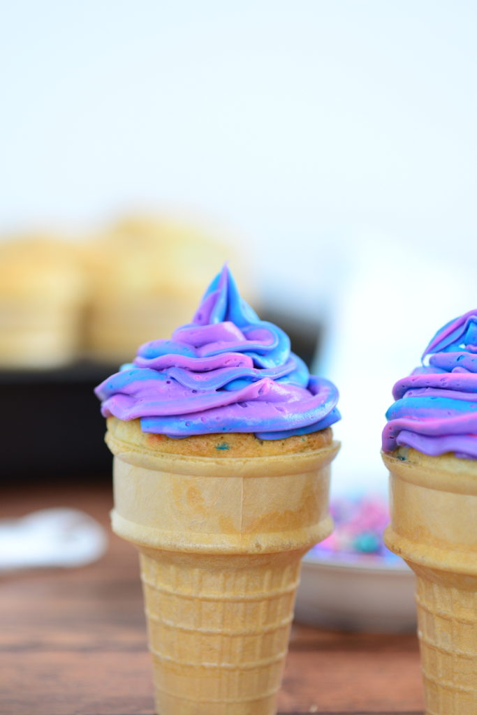 head on shot of bright icing piped onto ice cream cone cupcake