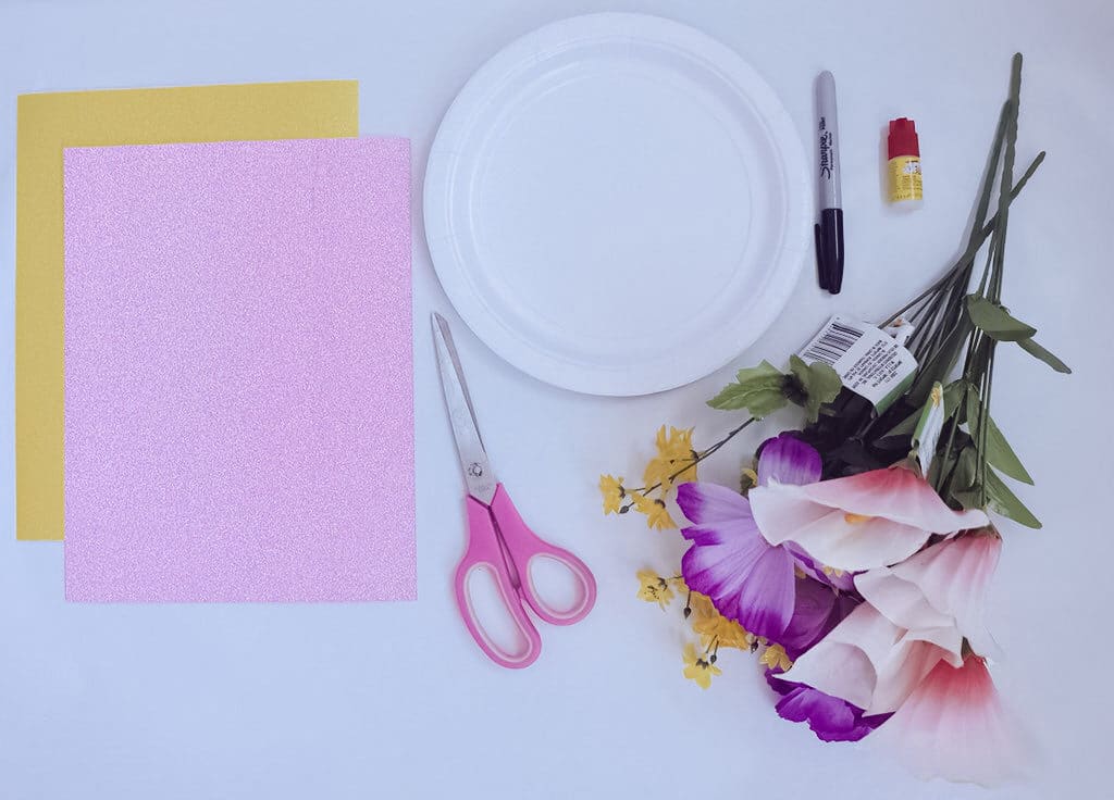 overhead view of supplies used for unicorn craft plate including fake flowers