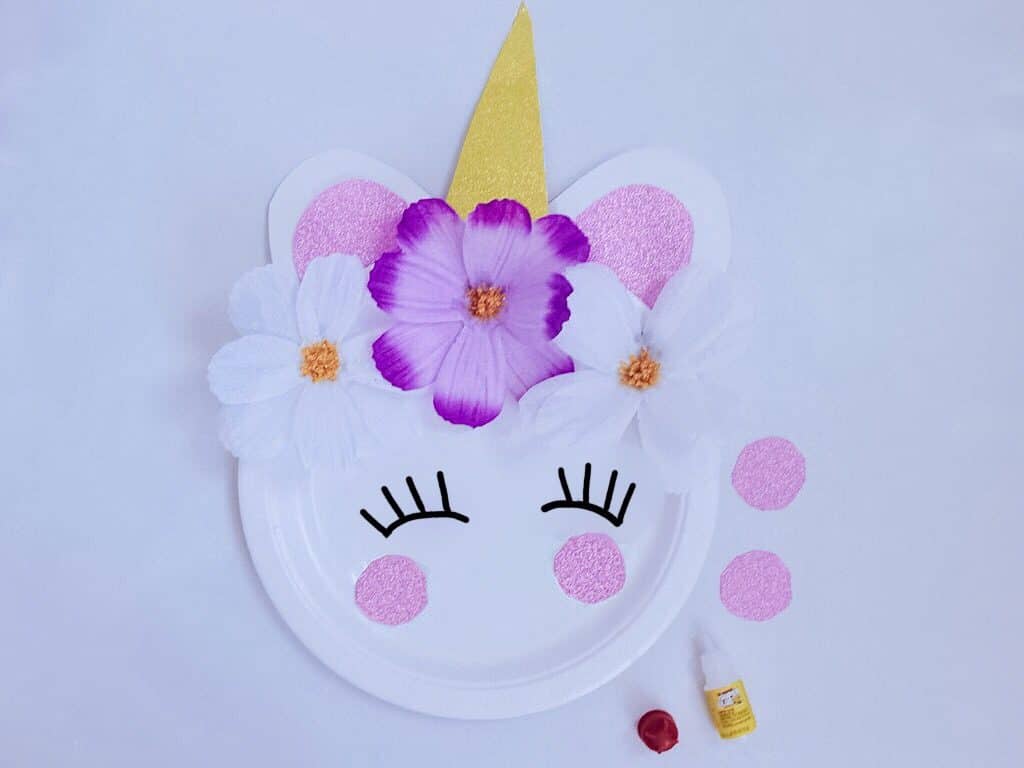 unicorn craft plate with eyelashes drawn on and pink paper dots on top