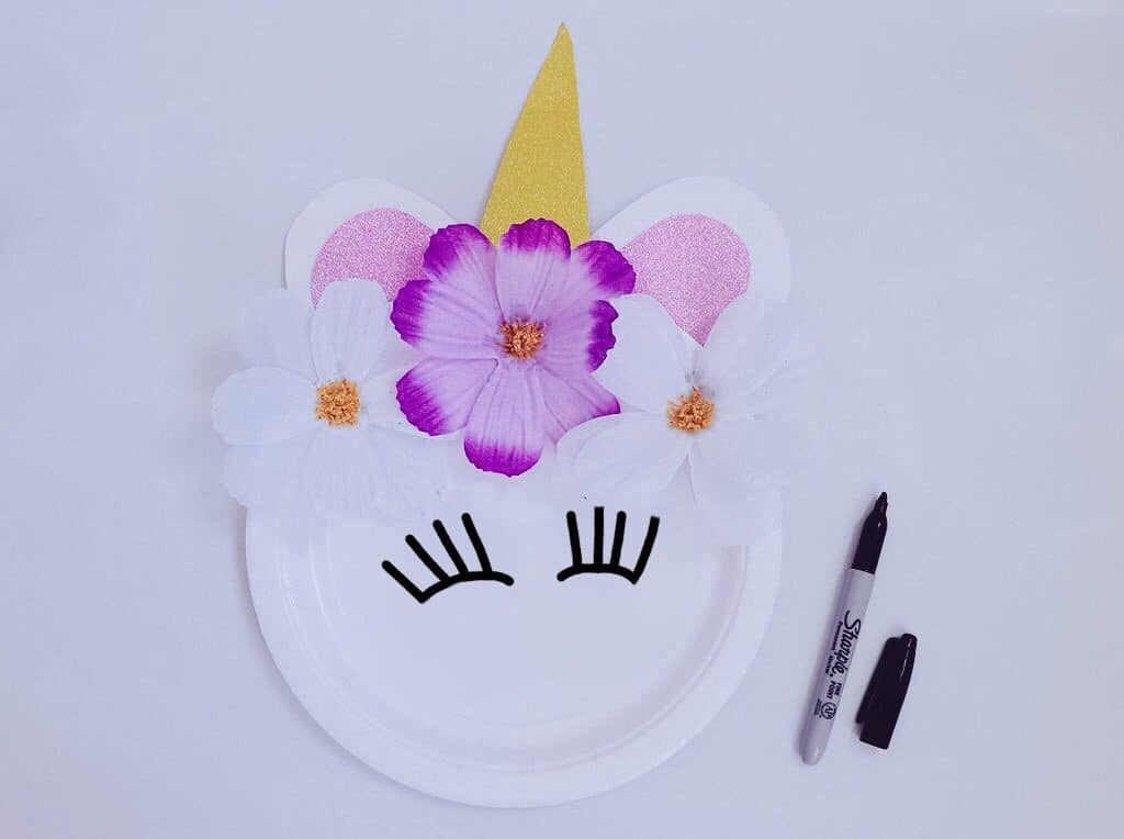 unicorn craft plate with eyelashes drawn on and flowers