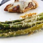 white plate with asparagus topped with parmesan cheese