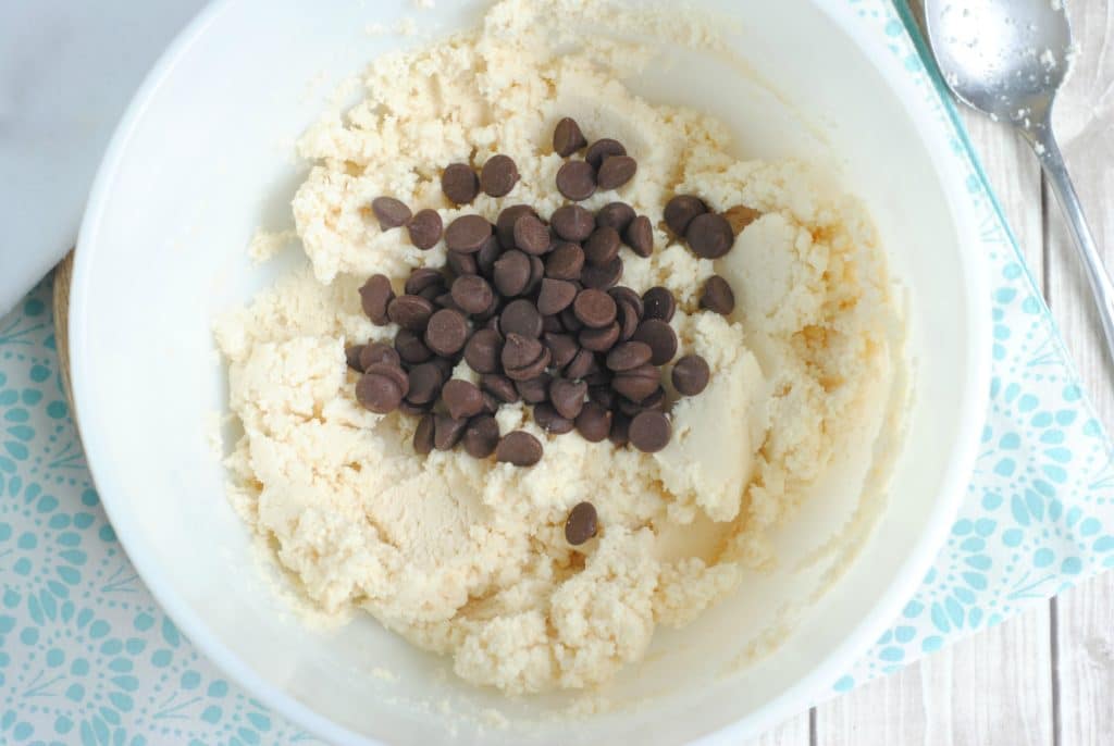 chocolate chips on top of edible keto chocolate chip cookie dough in white bowl