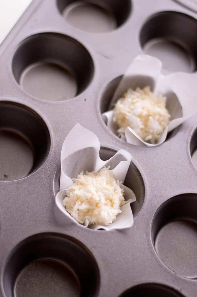 muffin tin with parchment paper and shredded coconut and evaporated milk mixture for coconut macaroon recipe