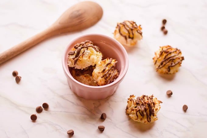 coconut macaroon recipe in a pink bowl next to chocolate chips and a wooden spoon