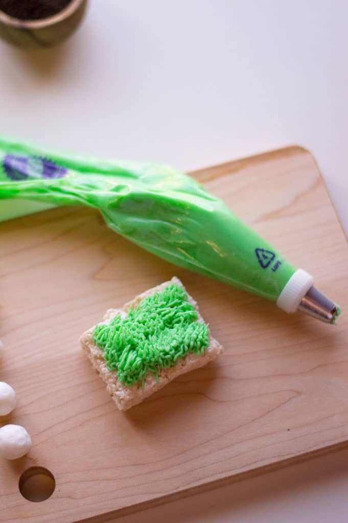 wilton decorating bag with green icing and rice krispies treat