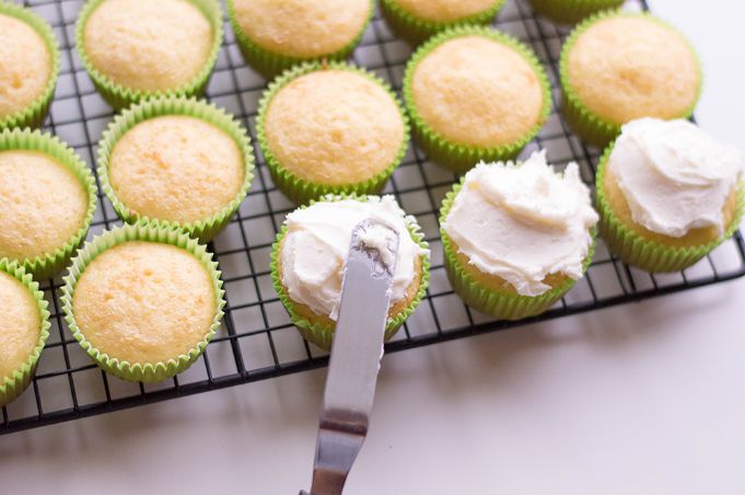 icing being placed on top of margarita cupcakes with knife