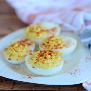 an overhead shot of deviled eggs on a white plate with a linen napkin