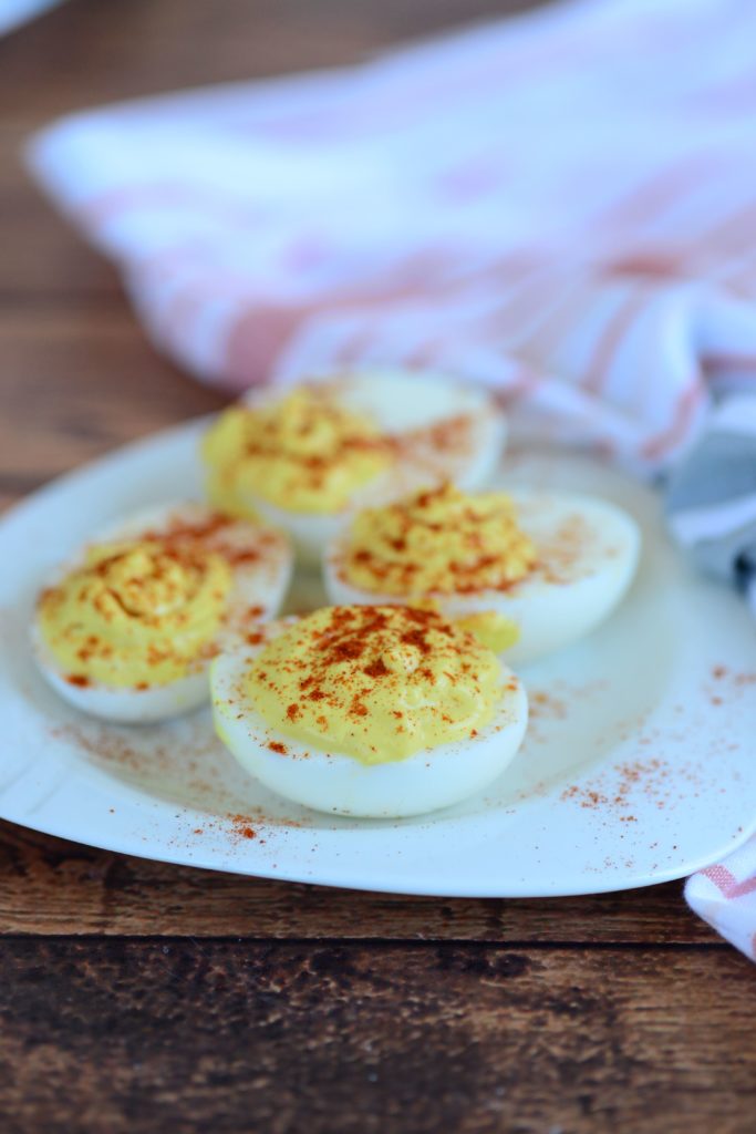 an overhead shot of deviled eggs on a white plate with a linen napkin