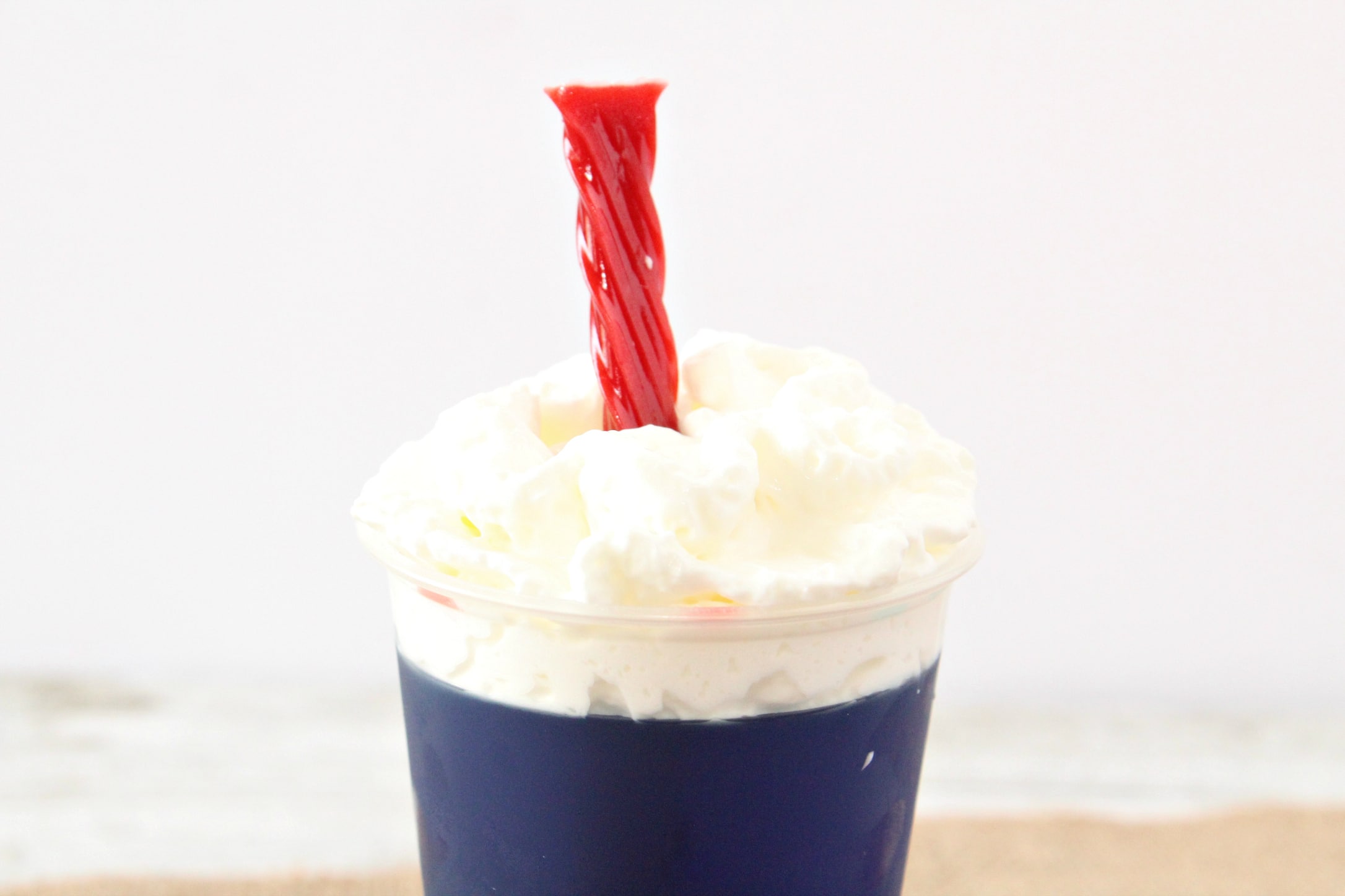 closeup of firecracker jello cups with whipped cream on top and red twizzler sticking out