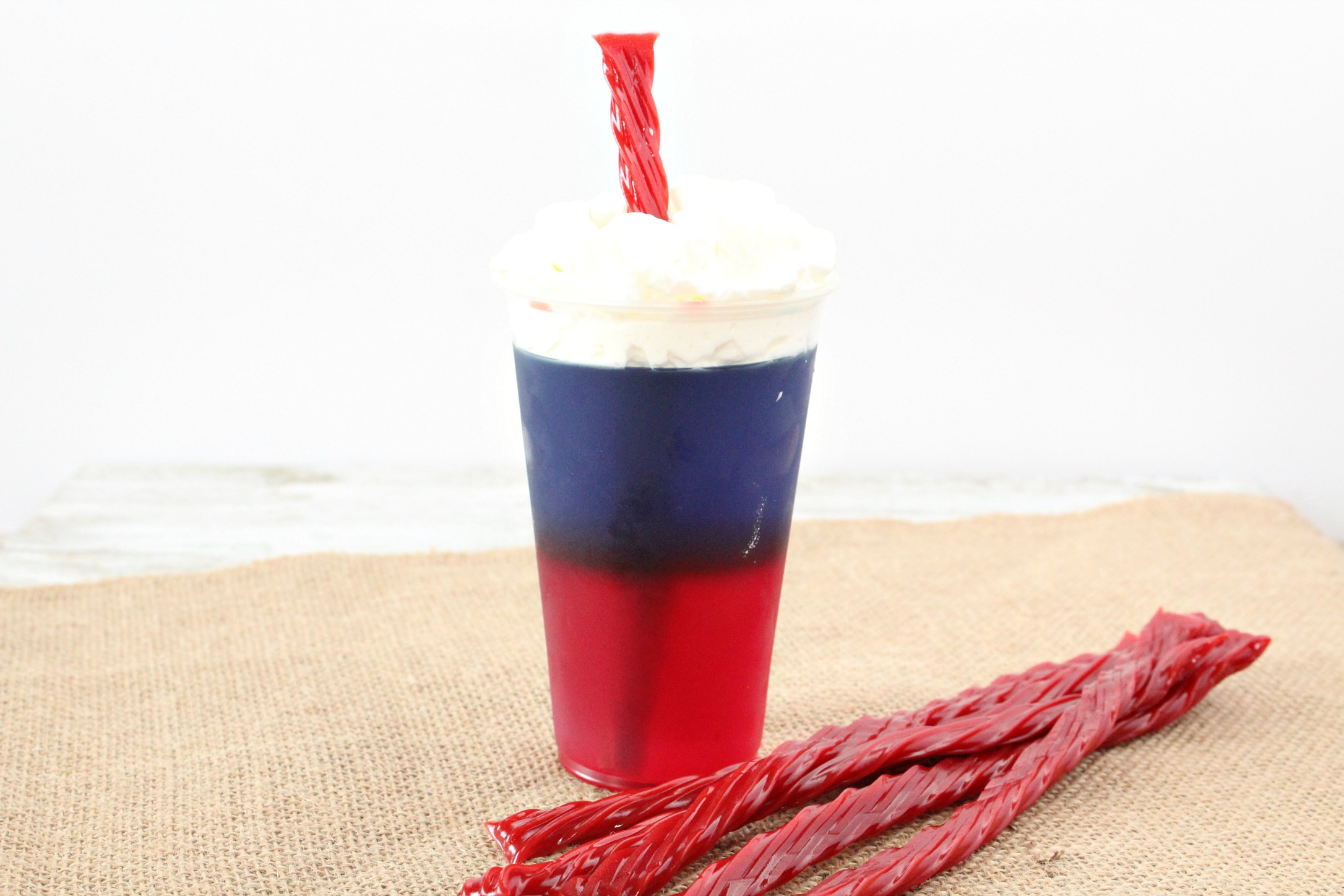 horizontal view of firecracker jello cups with twizzler sticking out of whipped cream