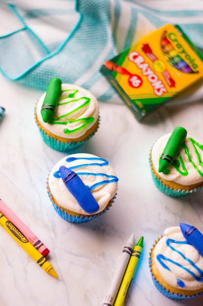 overhead view of various crayon cupcakes surrounded by crayons and crayon box