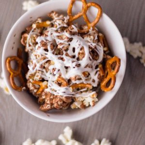 sweet and salty popcorn in white bowl with popcorn and pretzels