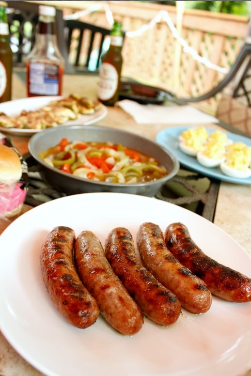 yuengling brats on plate with grilled peppers in background