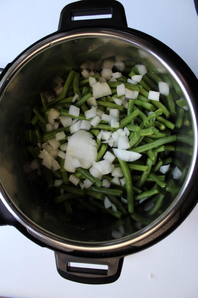 overhead shot of green beans and onions in instant pot