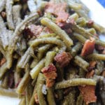 vertical shot of green beans with bacon on white plate
