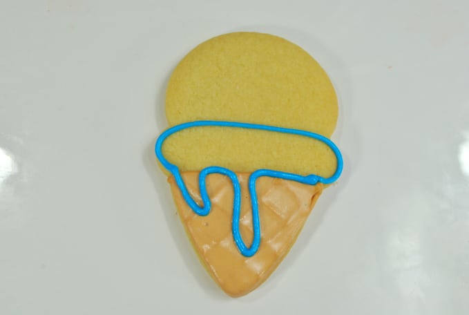 Using the blue icing, pipe an oval outline with ice cream dripping.