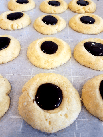 thumbprint cookies with chocolate filling on parchment paper
