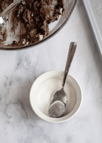 cookie dough in mixing bowl, sugar with spoon and ball of cookie dough