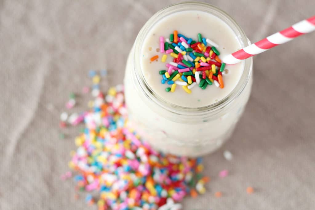 birthday cake smoothie in mason jar with sprinkles and straw