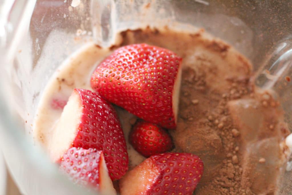 The ingredients in a blender for a strawberry smoothie