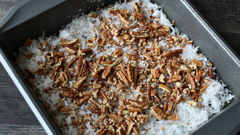 coconut and pecans in the bottom of a cake pan