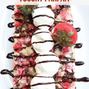 vertical shot of cereal and fruit frozen yogurt parfait on plate drizzled with chocolate syrup