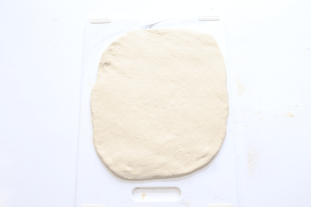 pizza dough rolled into rectangle shape on cutting board