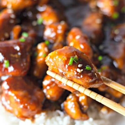 chopstick holding bourbon chicken piece